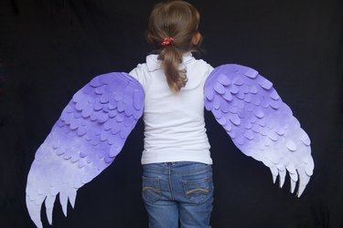 a little girl with a pair of purple and white diy bird wings.
