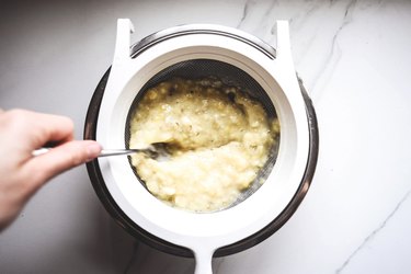 Use a fork to mash the bananas through the sieve.