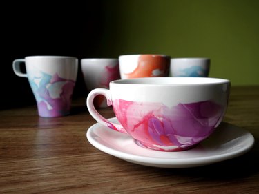 DIY Nail polish marbled mugs on table.