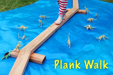 a child balancing on wooden planks laid on top of a blue tarp