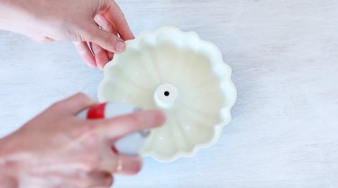 Coating a Bundt pan with baking spray.