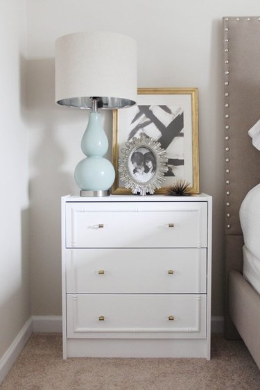 White nightstand with a blue lamp, picture, and photo frame