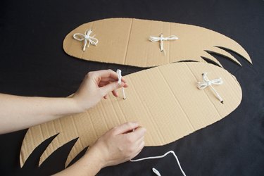 Attaching string to a pair of cardboard wings.