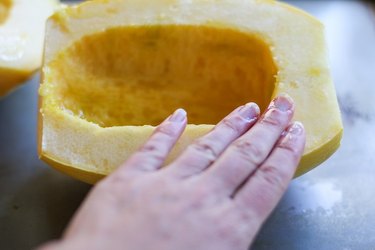 Olive oil being smeared on squash flesh