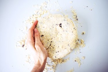 Hands shaping the rough dough into a mound.