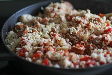 chicken, onion, rice, chorizo, and tomatoes in a paella pan