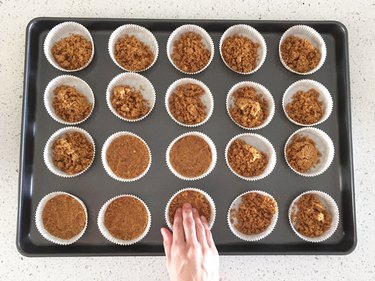 Pressing graham cracker crust into cupcake cups