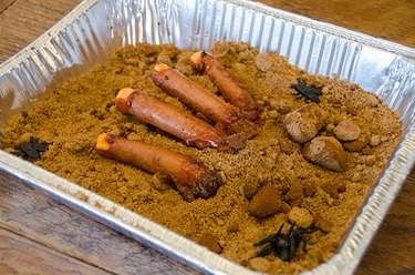 Cooked hot dogs on a bed of brown sugar that looks like sand and dirt
