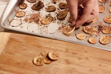 Baked banana chips on a metal baking pan.