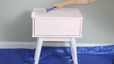 Rolling pink paint onto the nightstand