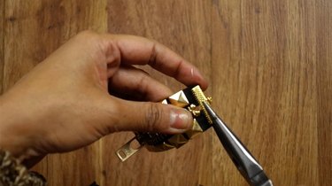 Attaching ribbon clamp to studded zipper bracelet.
