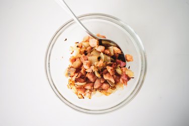 Fried onion and bacon set aside in a bowl.