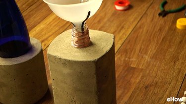 Adding tiki fuel to DIY concrete tabletop tiki torches out of used glass bottles.