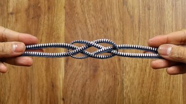 Tying a knot to make a knotted bracelet from a zipper.