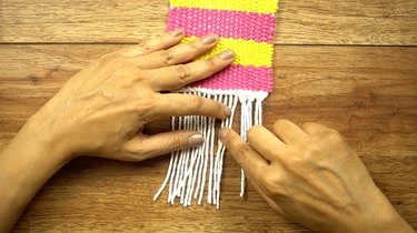 Creating a knotted fringe for DIY coasters on cardboard loom.