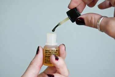 dipping a brush into a bottle of adhesive