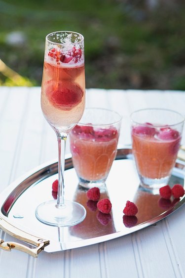 Silver tray with champagne flute of raspberry sorbetto mimosa and glasses of mini mocktails.
