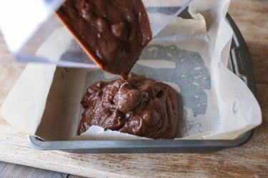 Brownie batter being poured into a baking dish