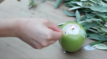 lighting an apple candle with a match