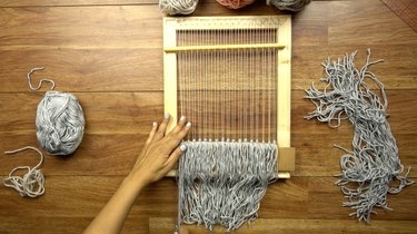 Adding fringe knots to woven wall hanging.