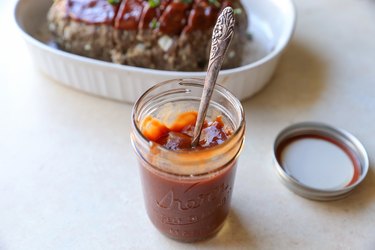 Jar of meatloaf sauce with meatloaf in the background