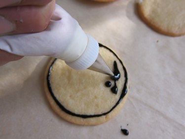 Pipe black icing onto cookie