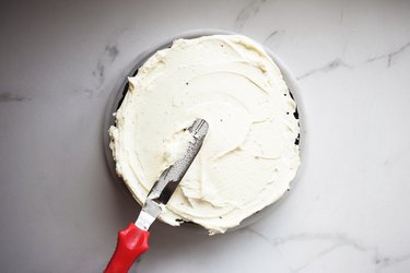 Use an offset spatula or butter knife to spread the buttercream frosting in a smooth layer.