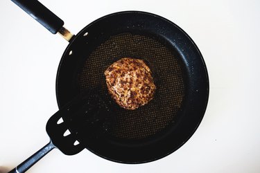 A finished burger patty in a frying pan.