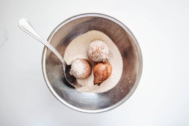 Rolling the Donut Holes in cinnamon sugar.