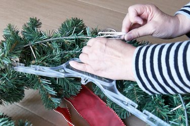 Attaching wreath to plastic hanger for storage.