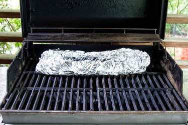 Baby back ribs wrapped in foil on the grill