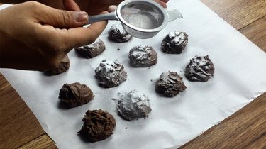 Dusting easy low-carb chocolate truffles with powdered sweetener.