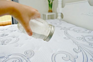 Spinkling DIY deodorizer on mattress