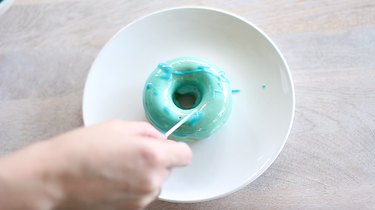 Dripping dark blue glaze on top of donuts