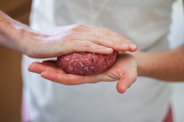 hands pressing meat into a burger patty