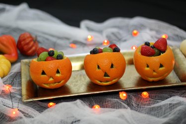 Three jack o'lantern fruit cups on a platter