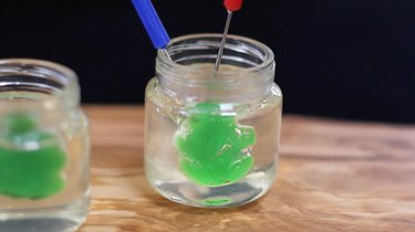 Inserting a gummy frog into the gelatin