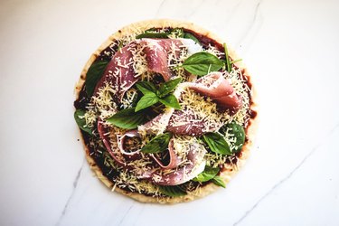 Balsamic Caramelised Onion, Prosciutto, Spinach and Parmesan Pizza ready for baking.