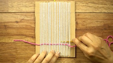 Weaving DIY coasters on a cardboard loom.