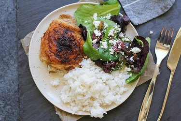 Chicken thigh on a plate with rice and salad