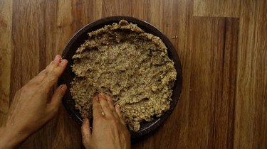 Pressing an almond meal pie crust into a pie pan.