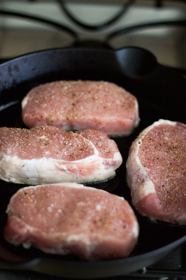 four pork chops in a cast iron pan on the stove