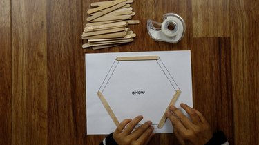 Laying down popsicle sticks for DIY hexagon shelves.