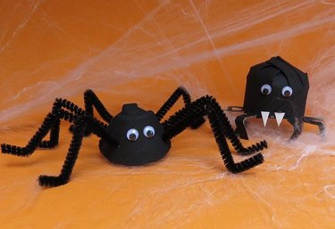 Two black homemade spiders with an orange background