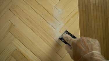 Applying wood filler to DIY herringbone pattern tabletop using paint sticks.