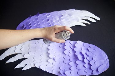 spray painting a diy pair of bird wings purple.