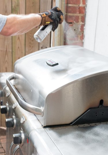 Applying stainless steel cleaner to the exterior of a gas grill