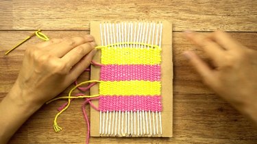 Weaving DIY coasters on a cardboard loom.