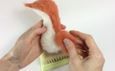Female hands holding a felted fox body and wool roving