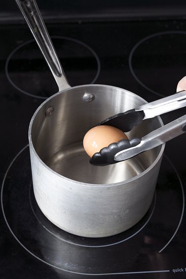 Placing an egg in a pot of water